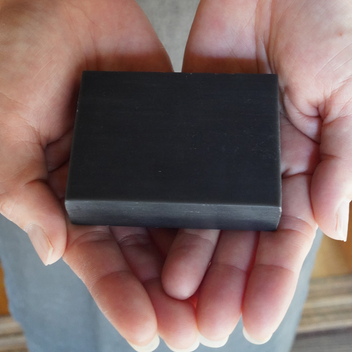 両手でそっと包み込まれた「竹と森の未來石けん」。毎日の暮らしの中で、無理なく自然を守り続ける「小さな循環」を象徴する一枚