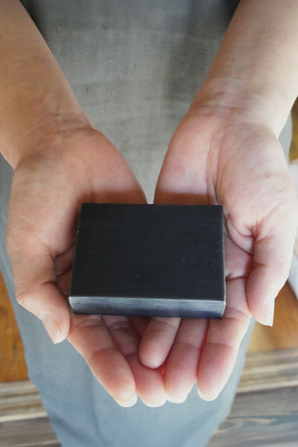 「竹と森の未來石けん」を両手でそっと包み込むように持つ様子。職人の手仕事と、商品への深い愛着を表現