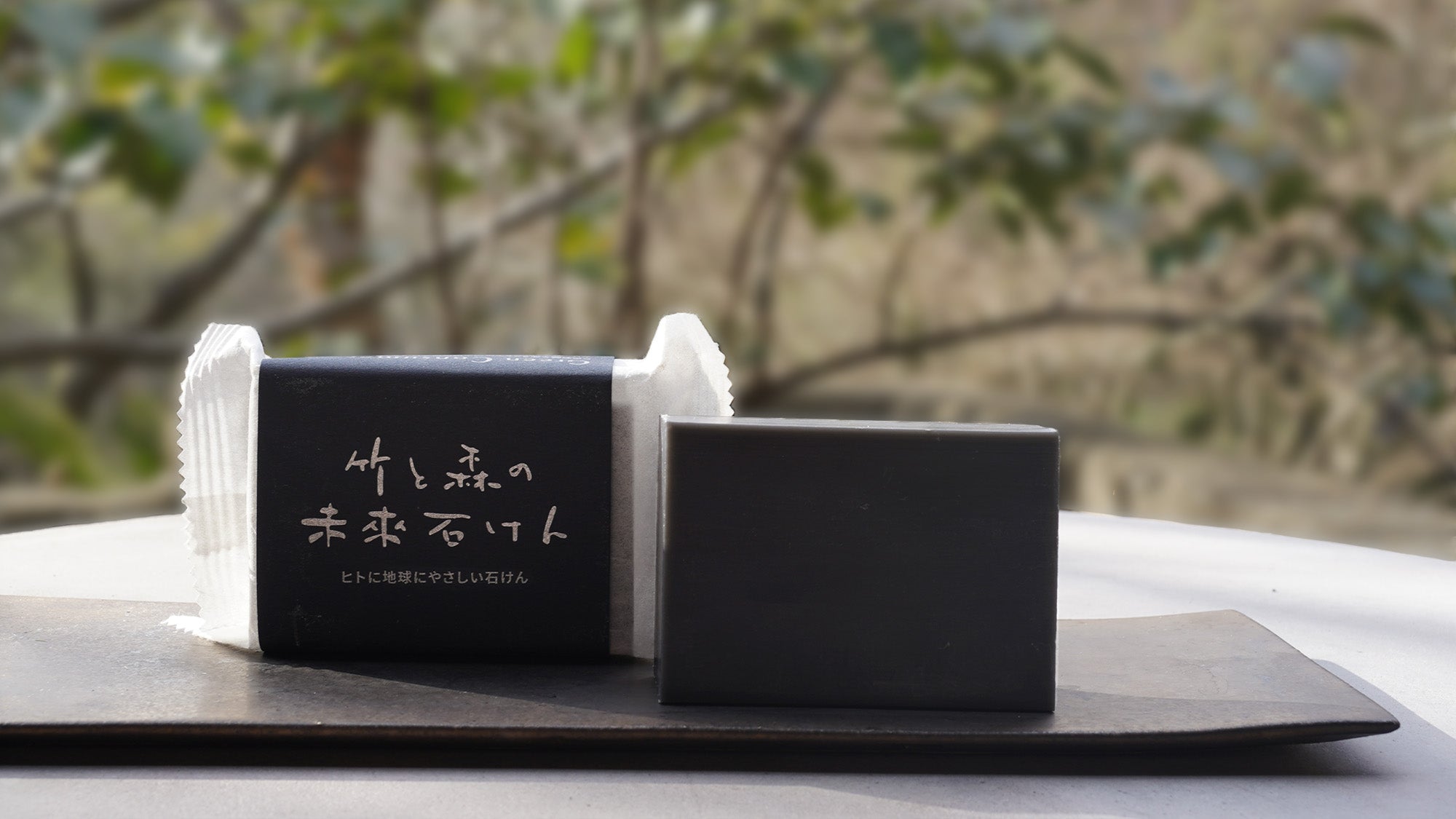 森を背景に置かれた「竹と森の未來石けん」のパッケージと石けん本体